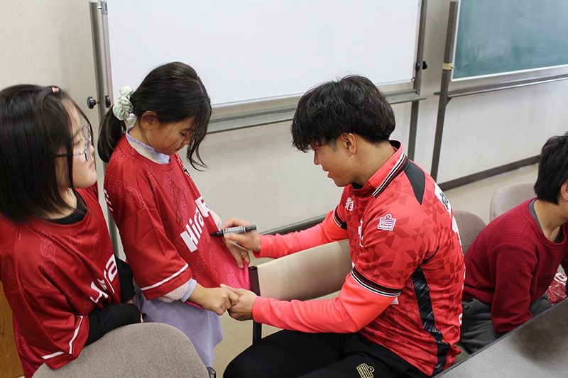 当社より子どもたちにTシャツをプレゼント。選手にサインをもらい喜ぶ子どもたち